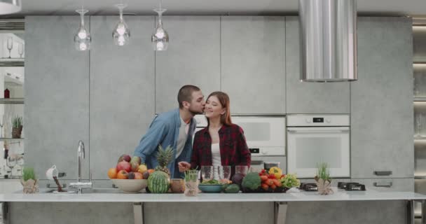 Una carismática pareja joven haciendo batido juntos en la cocina moderna, frente al camere, señora preparar todo para el hombre smoothie celebración de un zumo de naranja fresca . — Vídeo de stock