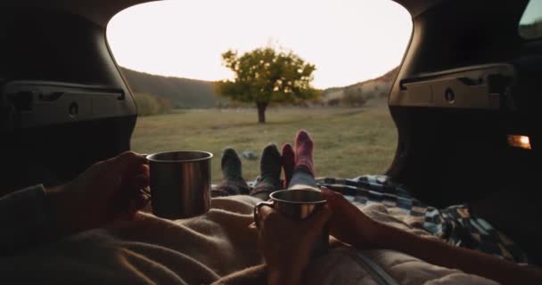 Rögzítés részleteit egy pár egy autó törzs közepén természet kényelmes zokni és a gazdaság egy vas csésze tea van egy relaxációs idő. 4k — Stock videók