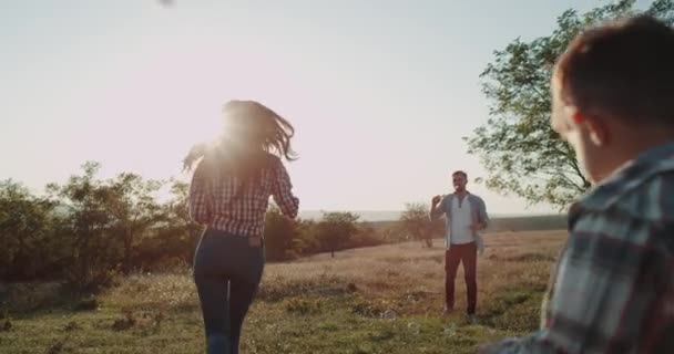 Bela família jovem duas crianças de três anos e um ano de idade, mãe e dar na natureza brincando juntos na natureza fazendo bolhas . — Vídeo de Stock