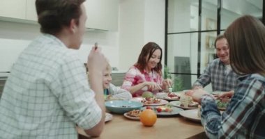 Birlikte akşam yemeği alarak büyük sevimli bir aile içinde modern bir mutfak masa.