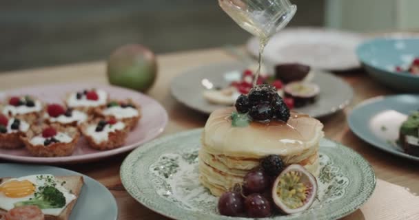 Närbild smaskiga pannkakor med blåbär i toppen och honung hälla på slow motion. — Stockvideo