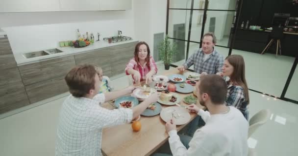 Glückliche Familie genießen die Mahlzeit zusammen, sie scheren hausgemachte Mahlzeit zusammen und verbringen eine schöne Zeit zusammen. — Stockvideo