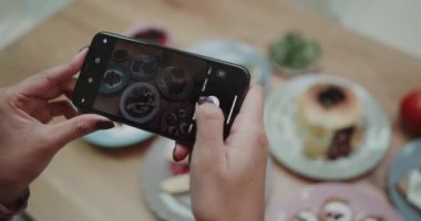 Bir kız lezzetli görünümlü yiyecek resimleri çekerken onun açısı mükemmel çalışıyor.