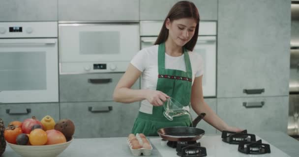 Bir Kız Sıcak Cızırtılı Tavada Yumurta Pişirme Yeşil Önlük — Stok video
