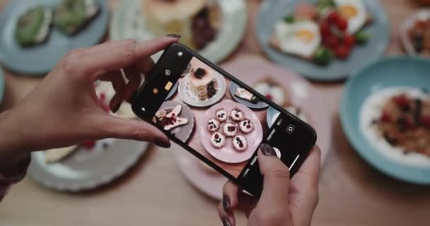 Uma menina tirando fotos em diferentes ângulos de uma comida . — Vídeo de Stock