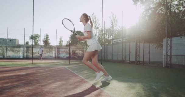Feliz esportiv mujer jugando al tenis en la cancha de tenis fuera . — Vídeo de stock