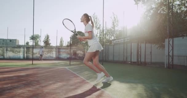 Glückliche sportliche Frau spielt Tennis auf Tennisplatz draußen. — Stockvideo