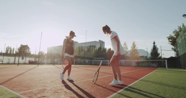 Δύο όμορφες κυρίες, ετοιμάζεται για το παιχνίδι τένις, χτυπώντας τα χέρια και αρχίζει το παιχνίδι γήπεδο τέννις. — Αρχείο Βίντεο