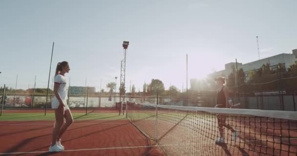 Vor dem Tennisspiel, zwei Spielerfrauen grüßen und Händchen halten, bevor das Spiel beginnt. — Stockvideo