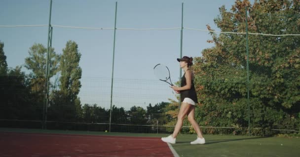 Sportiv nő verte a teniszlabda nagyon profi teniszpályán, egy izom lábakkal. — Stock videók