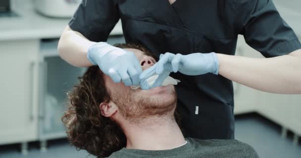 Dama dentysta umieścić pacjenta straży usta w pomieszczeniu kliniki stomatologicznej, zadowolony pacjent siedzi na fotelu u dentysty. — Wideo stockowe