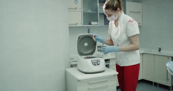 In einem modernen Labor medizinische Hilfe dabei, die Testwanne mit Blut aus einer Labormaschine zu entnehmen und die spezielle Box anzulegen. — Stockvideo