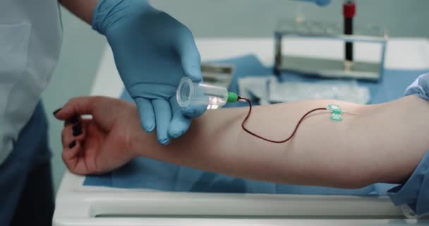 In einer modernen Klinik Details einer Blutentnahme bei einer Spenderin, der Entnahme des Blutes aus der Hand und der Aufnahme in einer Wanne. — Stockvideo