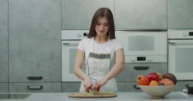 Modern mutfak yemek güzel bir Bayan tasarım ve kamera önünde bazı sebze kesme.