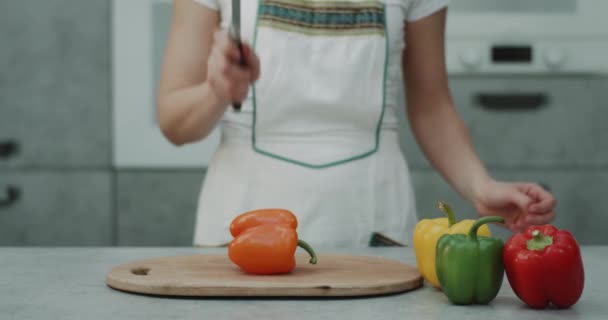 En el moderno video de la cocina la captura de una mujer cortar un pimiento dulce naranja en frente de la cámara de cerca. 4k — Vídeos de Stock