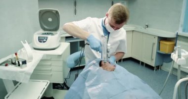 Bir kozmetik Oda Doktor hastasına vampir yüz prp, mavi sandalyeye bırakmasını hasta bir modern teknolojiyi kullanarak, yüz için modern yordamı yapmak