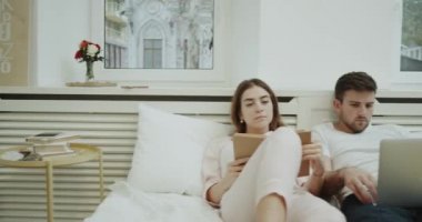 Okuma ve onların dizüstü yatakta kontrol bir modern yatak odası, Çift sabah. 4k