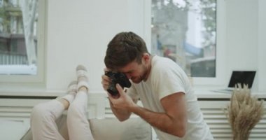 Adam kadını rahat yatakta anıları için bazı fotoğraf yakalama kadın gülümseyerek ve pijamayla poz. yavaş hareketleri. 4k