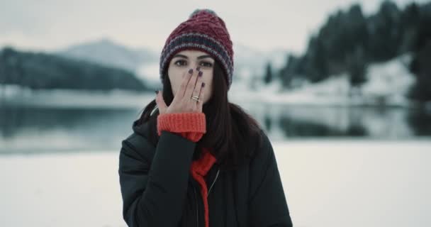 Zeer charismatische en goed uitziende jongedame toeristische aangekomen om geweldige plek tussen de besneeuwde berg met een grote vijver en bos achter, close-up vrouw op zoek direct naar de camera en zeer — Stockvideo