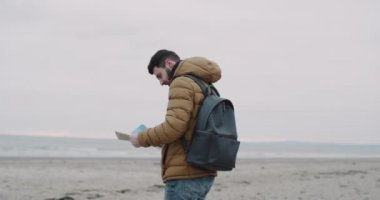 Deniz kenarında plajda harita kontrol tablet olan adam. Kırmızı epic vurdu. 4k.