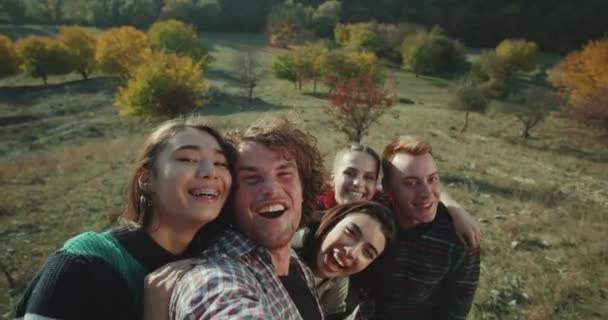 Amigos multiculturales tomando selfie video con cámara, en la naturaleza en la exposición, sonriendo y haciendo caras divertidas . — Vídeo de stock