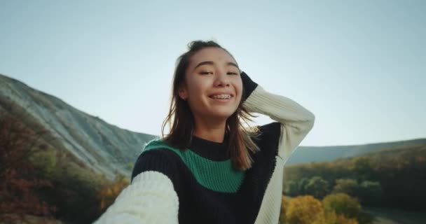 Cabello corto asiática joven dama tienen un tiempo de exposición en la naturaleza ella tomando selfie video y tener una gran sonrisa con corchetes. mociones lentas — Vídeo de stock