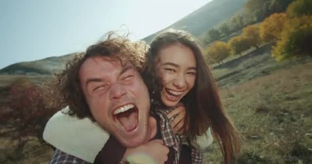 Una hermosa pareja multicultural pasando un buen rato juntos en medio de la montaña, tomando un video selfie y jugando divertido delante de una cámara . — Vídeo de stock