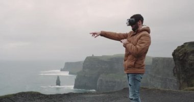 Turist adam bir Vr kullanarak ve şaşırtıcı yerde uçuruma, dağ ve mutlu duygu iyi tepesinde duran seyahat mutlu.