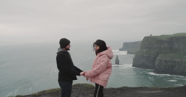 Beautiful young couple on the top of Cliffs of Moher, the man make a proposal to his lady she are very happy and elated , they hugging each other , they stand on the shore of Cliffs. 4k .shot on red — Stock Video