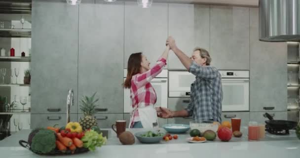 I ett modernt kök mogna par som spenderar romantisk tid tillsammans medan Matlagning mat de dacing mycket karismatisk. — Stockvideo
