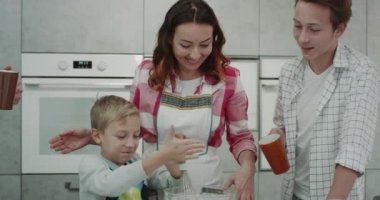 Sevimli aile hazırlanıyor birlikte kahvaltı, modern bir mutfak tasarımı bir el mikseri ile tüm malzemeyi karıştırma küçük çocuk. 4k