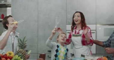 Olgun Anne kabarcıklar yapma bir modern mutfakta iki oğlu ile oynarken.