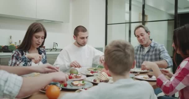 Hora de comer para una gran familia que sirve y come con hambre la comida y tienen un gran ambiente en una cocina moderna . — Vídeo de stock