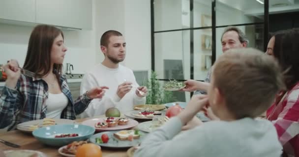 Hermoso ambiente familiar en la mesa de la cena esquilando la comida y comiendo un almuerzo saludable todos juntos . — Vídeos de Stock