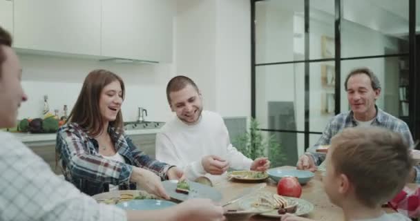 Almuerzo familia grande pasar un buen rato juntos esquilando el plato de comida saludable. 4k — Vídeos de Stock