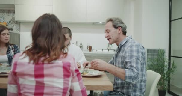 Middagen för en karismatisk stor familj de tar en hemmagjord hälsosam mat och spendera en härlig tid tillsammans medan du chattar med varandra i ett modernt kök — Stockvideo