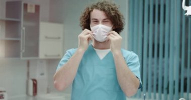 Genç diş hekimi adam ya da düz belgili tanımlık fotoğraf makinesi ve ameliyat maskesi ve mutlu büyük gülümseyen kalkış için seyir hastane closeup Doktor, o sahip mükemmel bir beyaz dişler ve karizmatik yüz.