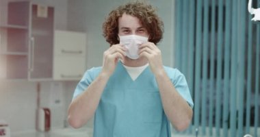 Hastane çok karizmatik genç doktor veya cerrah kalkış Ameliyat maskesi ve kamera ve gösterme önünde büyük gülümseyen bir büyük gibi