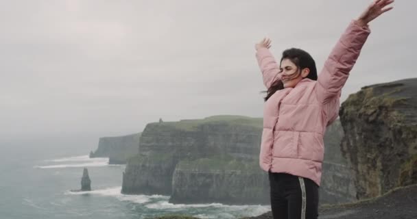 海と風景の眺めを楽しんで幸せな崖の上に素敵な若い女性は、彼女が非常に幸せと感動の場所. — ストック動画