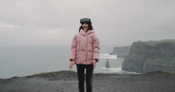 Young woman wearing VR , virtual reality glasses on the top of the Cliffs and have some fun with them , VR concept. slow motions — Stock Video