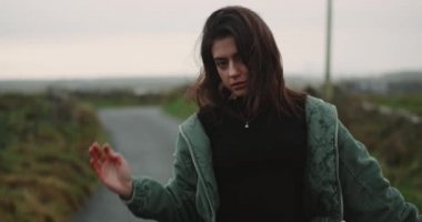 Yol kırsal, ortasında bir güzel bayan esmer kamerayı düz seyir ve tutkuyla, akşam saat hareket portresi.