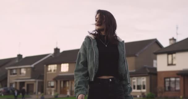 Walking lady through the street pensively in a windy day , she looks somewhere far , background beautiful house. shot on red epic — 图库视频影像