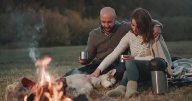 Doğa kamp ateşi husky köpekleri ile güzel çift demir Kupası birbirlerine sarılma ve güzel vakit geçirmeyi bir sıcak çay ile bir arada tutan iyi eğlenceler.