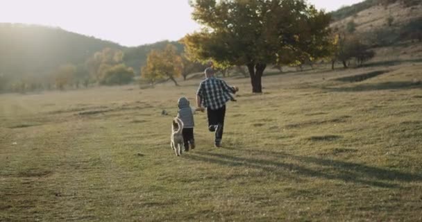 Niesamowite dzień rodziny tata z synem uruchomiona razem obok ich pies husky w nature, piękny widok. — Wideo stockowe