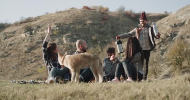Φορά πικνίκ φθινόπωρο, δύο οικογένειες με ένα παιδί και ένα χαριτωμένο μικρό σκυλί Χάσκι έχουν μια ζεστή βραδιά μέσα στη φύση — Αρχείο Βίντεο