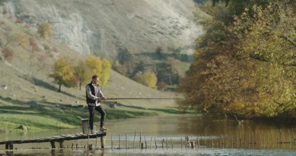 Bella giornata di sole un uomo cattura il pesce dal lago, alzarsi su un ponte . — Video Stock