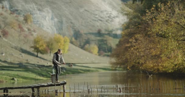 Tiempo de pesca el hombre tiene una recreación en la naturaleza, la captura de peces desde el puente . — Vídeo de stock
