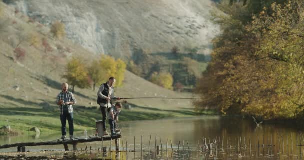 Jeden mały chłopiec z dwoma facetami, wędkowanie na jeziorze w nature. — Wideo stockowe