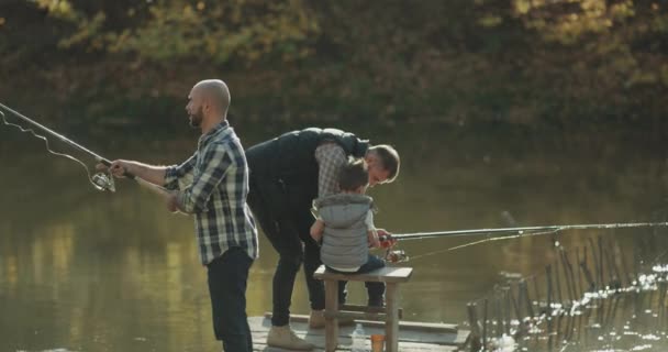 Крупный план рыбаков на мосту ловить рыбу, папа поощрял своего сына на рыбалку . — стоковое видео