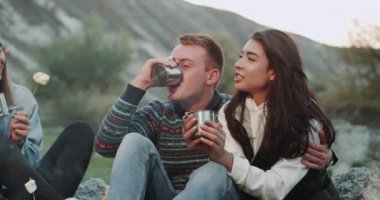 Gençleri, şekerleme yemek ve şenlik ateşinde bazı sıcak içecekler içme kamp closeup inanılmaz grup.